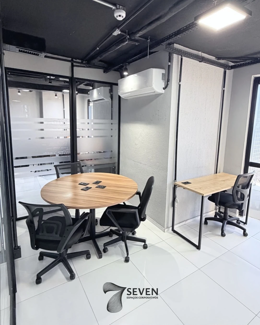 Sala climatizada com mesa redonda e estação de trabalho